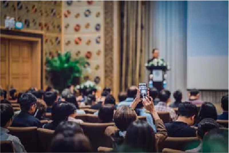 An audience filming a speaker at a conference